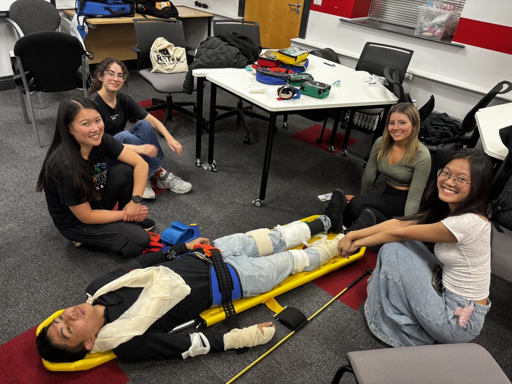 Group of students learning spinal board techniques with CFR equipment